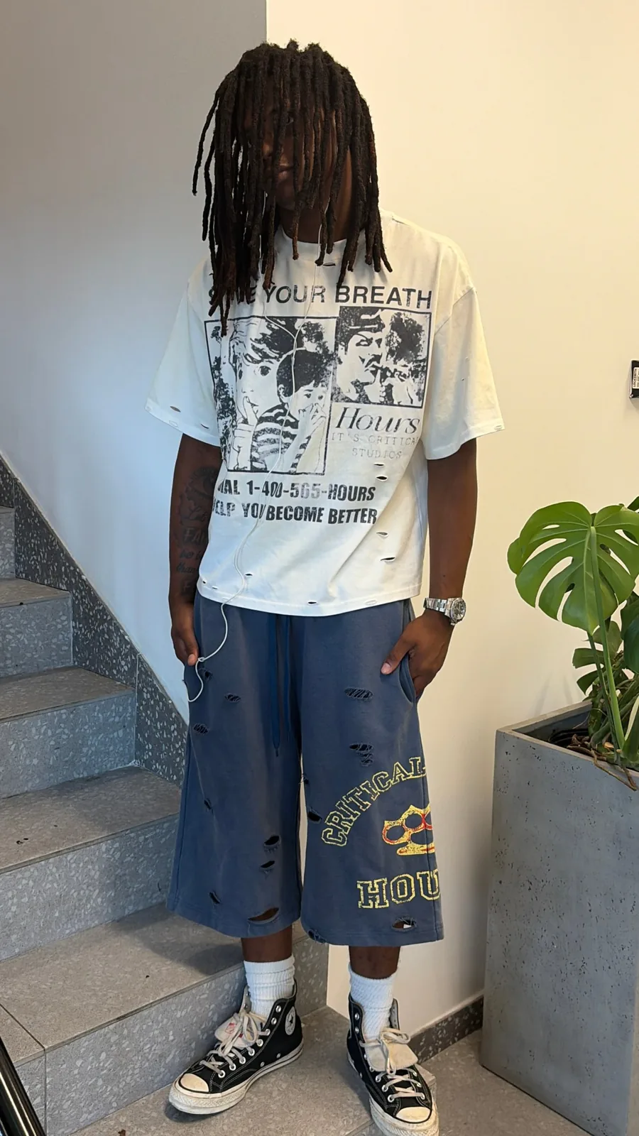 Model in the Pick Up The Phone tee and navy shorts on a stairwell